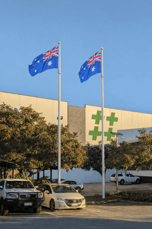 Tapered aluminium flagpoles by Urban Aluminium flying Australian flags in front of a the Urban Aluminium manufacturing facility building.